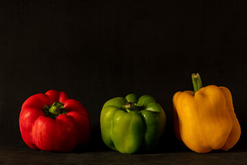 three multi-colored peppers posing for the photo on a dark background. - 379706790