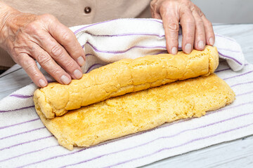 Close up of a senior woman hands rolling a just baked sponge cake