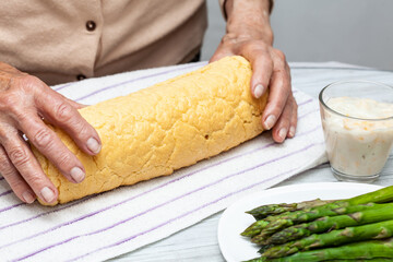 Close up of a senior woman hands rolling a just baked sponge cake