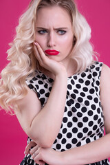 Portrait of a close-up of a young blonde woman with a severe dissatisfied look full of annoyance...