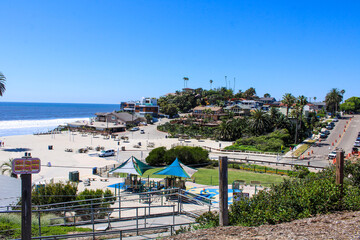 gorgeous shot of the blue ocean water, lush green palm trees and beach houses with people walking...