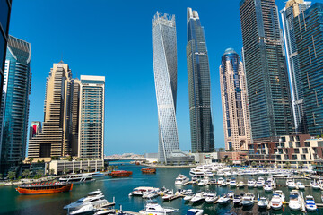 Fototapeta na wymiar Stunning panoramic view of Dubai Marina skyline, yachts and boats moored at the pier on a bright sunny day. Dubai, United Arab Emirates.