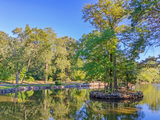 Obraz premium Reflective landscape park pond in late afternoon