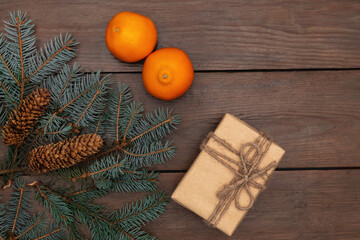 New Year composition on a wooden table. Christmas tree branches, spruce cones, gifts and tangerines.