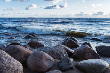 Obraz premium Photo of the rocks on the beach of the finnish bay in St. Petersburg. Choppy sea and a cloudy sky on the background