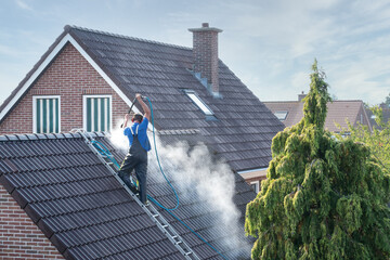 Cleaner with pressure washer at roof house cleaning roof tiles - obrazy, fototapety, plakaty