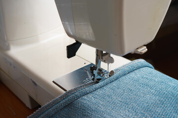 sewing machine. the process of sewing a decorative cord of blue fabric.