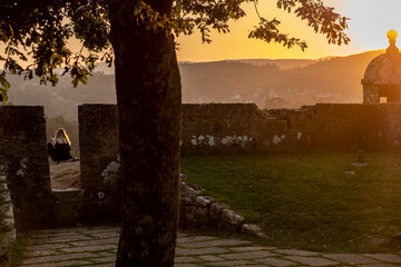 An unrecognizable girl contemplates the sunset. Walls of the fortress city of Valença do Minho. Portugal. Life style.