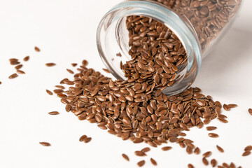 Macro photo of raw flax seeds in glass jar on white background for supplement and diet product concept