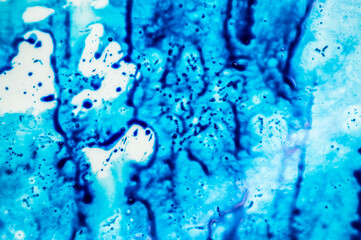 Blue refill ink spilled onto the white sink and the ink blended into abstract drops and patterns.