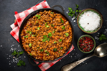 Bolognese sause in iron plate at black table.