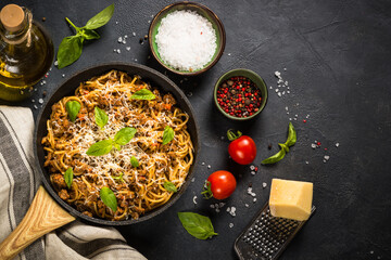 Pasta Bolognese in the skillet at black table.