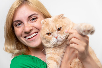 Studio portrait of an attractive woman with braces holding a cat in her hands, isolated on a white background