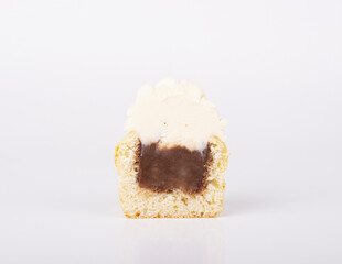 The cupcake is cut in half, with a chocolate filling and white vanilla icing