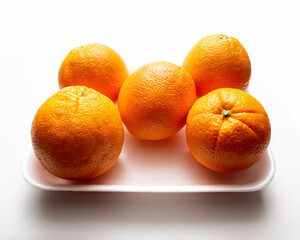 Group of oranges on a polystyrene tray on white background, supermarket presentation, high angle camera shoot, horizontal arrangement