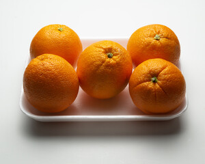 Group of oranges on a polystyrene tray on white background, supermarket presentation,  horizontal arrangement , high angle camera view