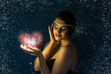 Christmas portrait of a young brunette girl holding a glowing ball made of LED lights in her hands.