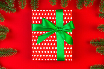 Top view of fir tree branches and gift box on colorful background. Christmas time concept with empty space for your design