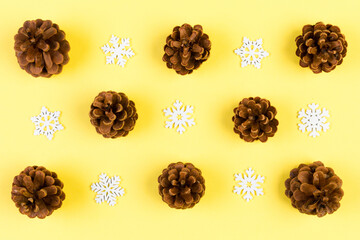 Top view of New Year ornament made of white snowflakes and pine cones on colorful background. Winter holiday concept with empty space for your design