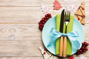 Top view of plate, fork and knife served on Christmas decorated wooden background. New Year Eve concept with copy space