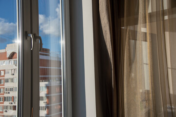 Fragment of a room window through which an apartment building is visible.