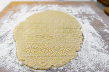 Dough rolled out on the table with a New Year's pattern. Making cookies on the New Year's table, a festive treat.