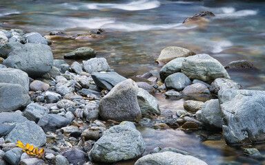Fototapeta na wymiar Flussbett mit Kies und großen Steinen, Langzeitbelichtung, Ruhe und Entspannung