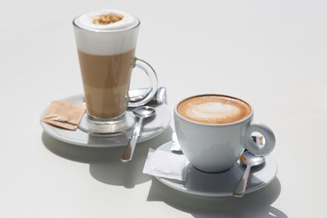 Cups of coffee with bright sunlight on table