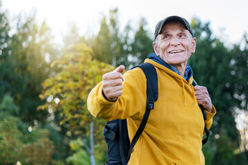 Naklejka premium old traveler man with smile on face wearing cap calling people to adventure in mountains forest background