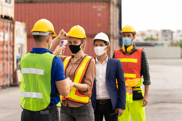 Selective Focus. Foreman using an infrared thermometer measuring temperature to check the worker before working at container yard on business day that covid-19 coronavirus is epidemics. 