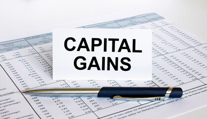 Text Capital Gains on white card with blue metal pen on financial table