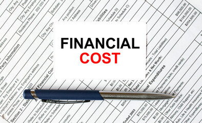 Text Financial Cost written on a business card lying on financial tables with a blue metal pen