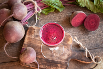 Red beet juice in a glass on a wooden table