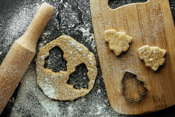 close up of christmas baking background. raw homemade rolled dough with cut out shapes on kitchen...