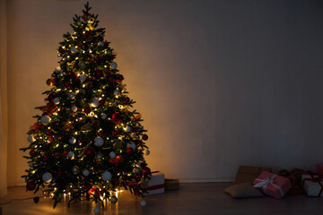 Christmas tree with gifts of garland lights at night on New Year's Eve in the interior room