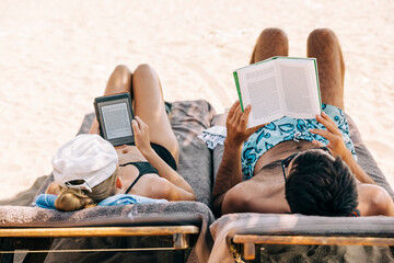 Couple reading ebook and book on beach