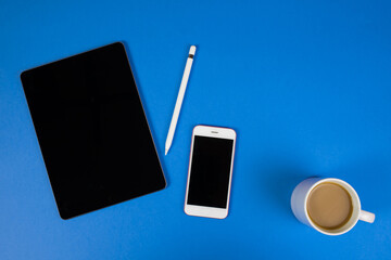 
Tablet and electronic pen with a cup of coffee on a blue background. Template blank. A glass of coffee. Break at the office.