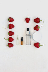 Transparent cosmetic serum in bottle with pipette next to red fresh strawberry. copy space