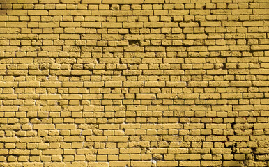 A clean wall of old yellow painted brick.