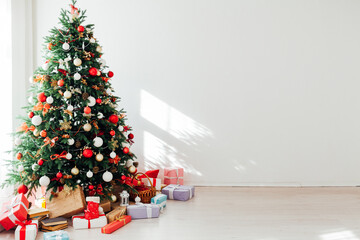 Christmas tree with gifts of garland lights for the new year in the interior of the white room as a backdrop