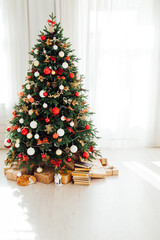 Christmas tree with gifts of garland lights for the new year in the interior of the white room as a backdrop