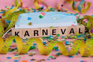 Fototapeta na wymiar German word KARNIVAL on wooden blocks under a face mask with confetti and streamers