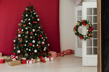 Christmas tree with gifts of garland lights for the new year in the interior of the room as a red background