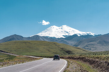 Fototapeta premium Scenic road view of the highest peak in Europe, mount Elbrus with green hills on a Sunny summer day.