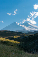 Fototapeta premium Scenic view of the highest peak in Europe, mount Elbrus with green hills on a Sunny summer day.