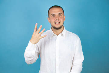 Russian business man wearing white shirt standing over blue background showing and pointing up with fingers number four while smiling confident and happy.