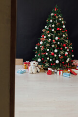 Christmas tree decorated with toys with gifts in the interior of the room black background new year