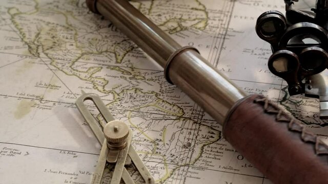 Vintage telescope with compass and sextant at old map of the 17th century while pitching
