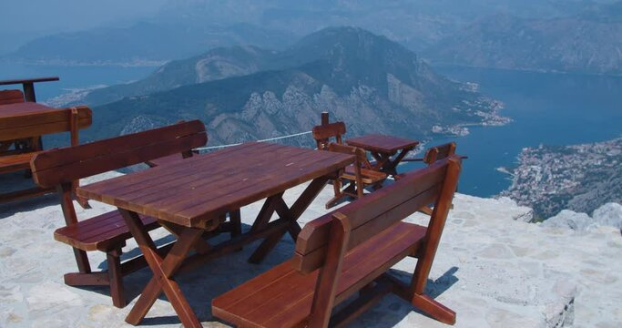 Street cafe in the mountains with a view of the mountains and the bay. Wooden tables and chairs. High quality 4k footage
