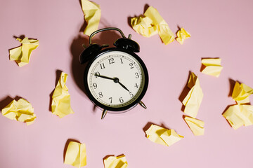 The concept of deadlines and the generation of ideas. Top view of classic alarm clock with crumpled...